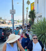 Community lining up on the sidewalk for food distribution.